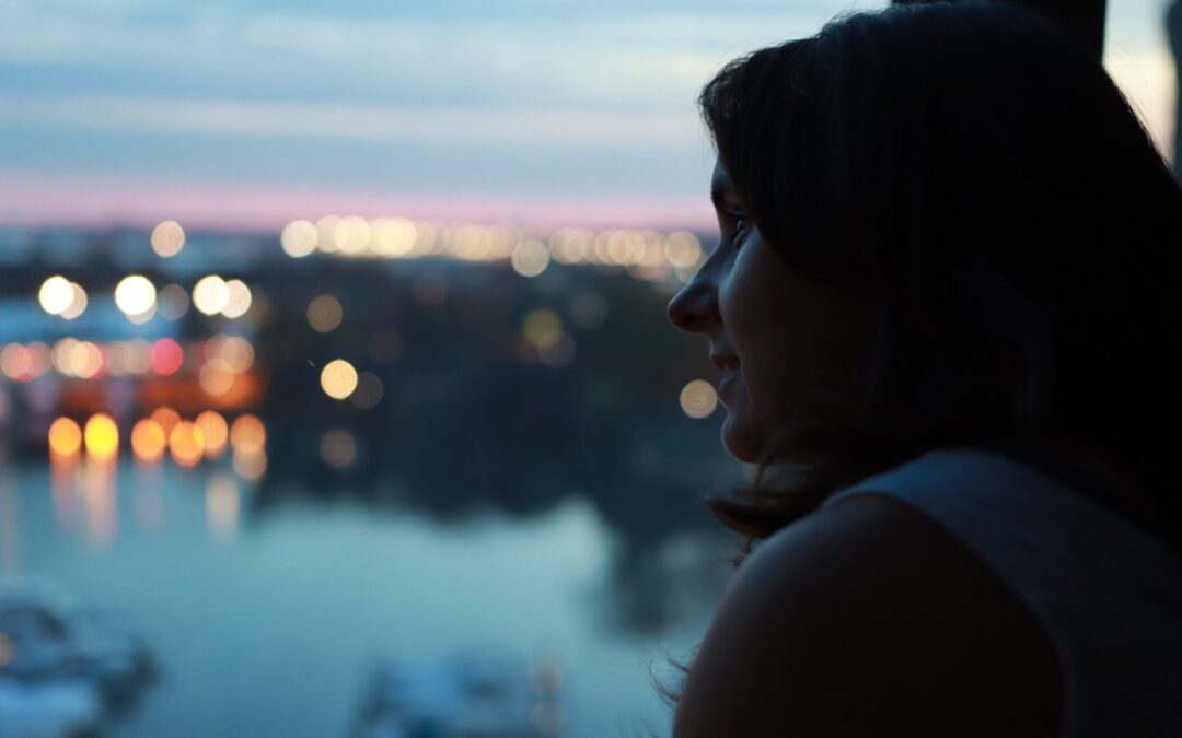 Woman standing by a window reflecting on the power of silence in leadership and communication